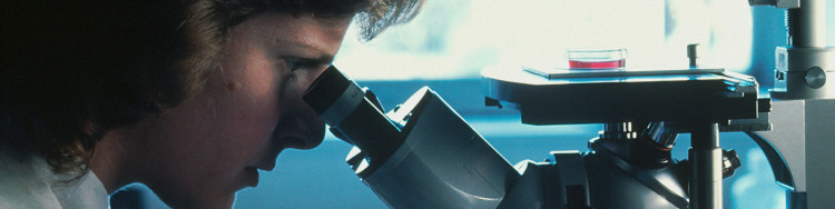 una mujer mirando a través de un microscopio