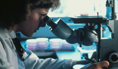 una mujer mirando a través de un microscopio