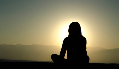 una mujer sentada viendo hacie el sol